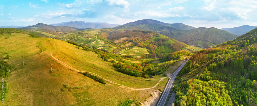 Highway in mountains. Evening sunlight on hills. Spring green rural landscape.