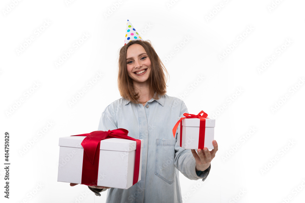 A happy young woman in a festive hat holds two gifts on a white background A happy young woman in a festive hat holds two gifts on a white background
