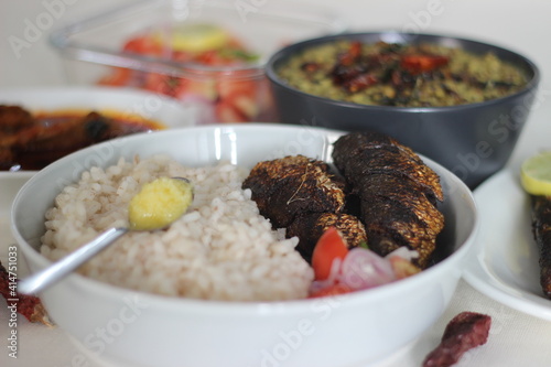 Kerala meals with red rice, sardines curry, sardine fry and coconut based green gram curry photo