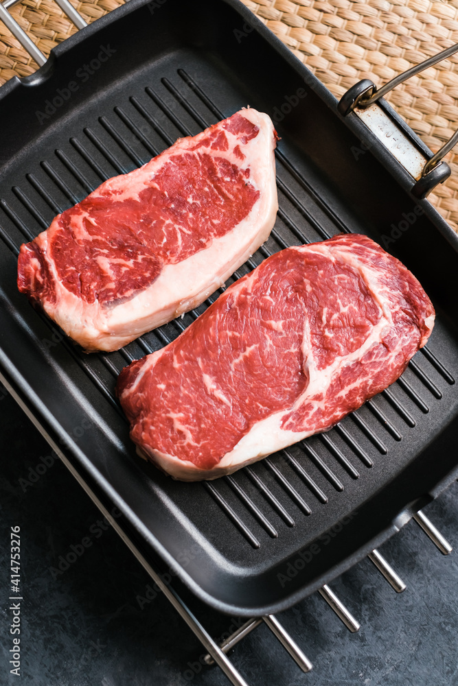 Raw rib eye and striploin New York beef steak on black grilling pan, top view. Raw rib eye and striploin New York beef steak on black grilling pan, top view.
