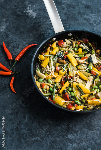 Fresh asian vegetables mix, Thai wok in a black pan on the black background with copy space. Healthy food