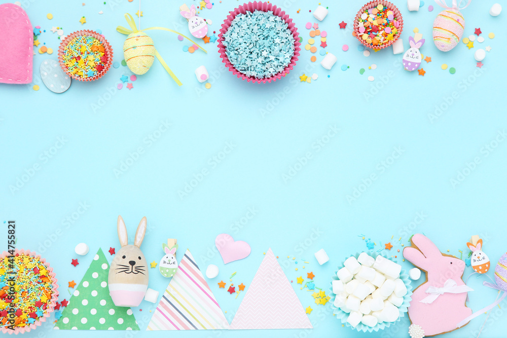 Easter concept. Colorful sprinkles, eggs, paper flags and marshmallows on blue background
