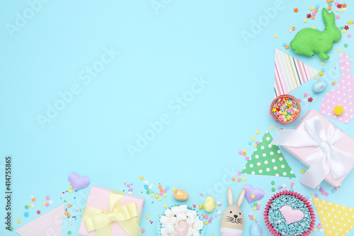 Easter concept. Paper flags white gift boxes, eggs and sprinkles on blue background