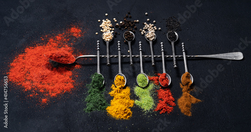 Fototapeta Naklejka Na Ścianę i Meble -  Spices and condiments in spoons for cooking on black background