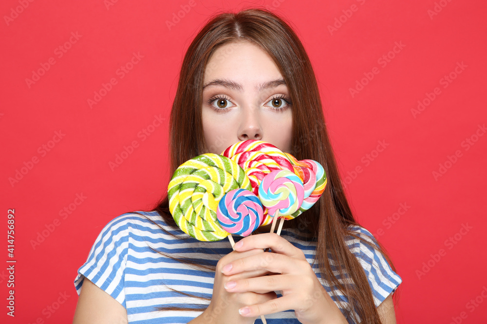 Beautiful girl with colorful lollipops on red background