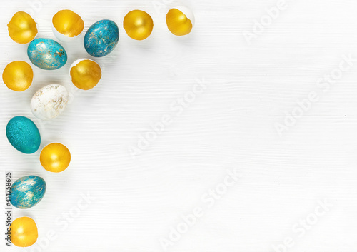 Easter background with multicolored hand painted eggs and golden eggshells on white wooden background with copy space. Easter ad banner with turquoise and gold eggs.