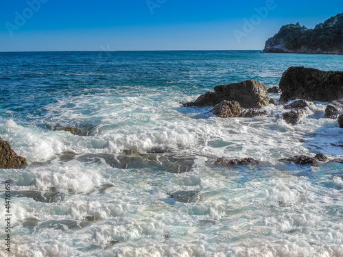 Fotografia waves hitting rocks in the summer sun in Budva, Montenegro