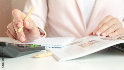 close up of woman hands with calculator counting and taking notes to notebook