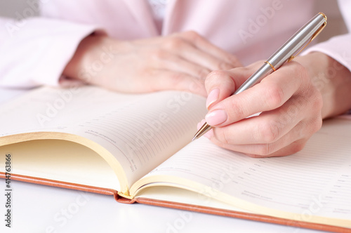 a woman writes down information with a pen in a diary