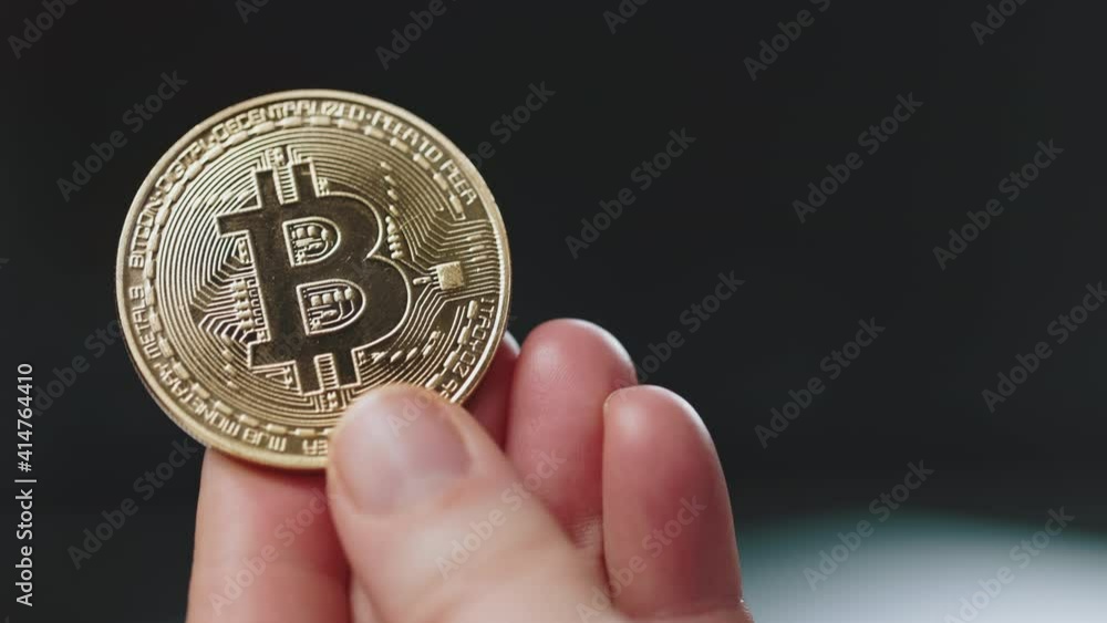 Golden shiny bitcoin that holding man in hand. Coin with profit. Virtual popular currency. Concept of trade and banking. Golden shiny bitcoin that holding man in hand. Coin with profit. Virtual popular currency. Concept of trade and banking.