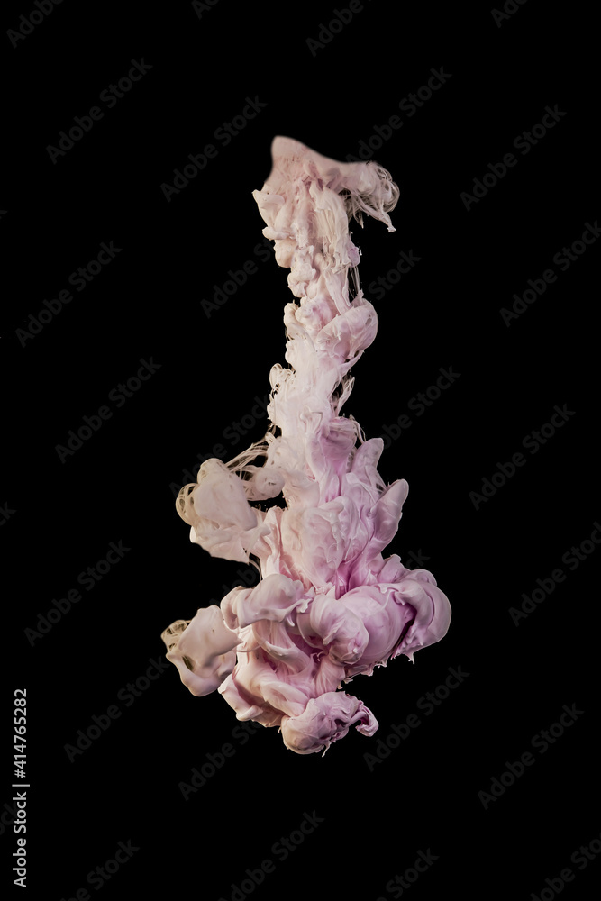 Ink dropped into the water and photographed while in motion. Paint swirling in water. Pink cloud and smoke of paint in water isolated on black background.
