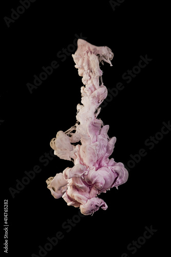 Ink dropped into the water and photographed while in motion. Paint swirling in water. Pink cloud and smoke of paint in water isolated on black background.