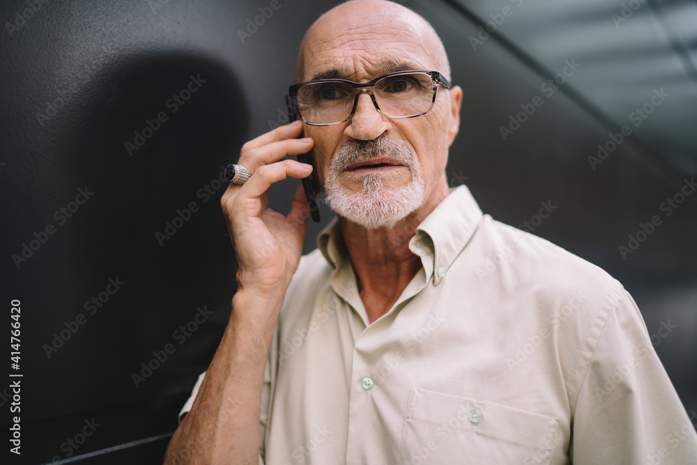Close up of serious male senior in optical spectacles for provide eyes correction making international smartphone conversation in roaming, Caucasian man in classic glasses have consultancy call Close up of serious male senior in optical spectacles for provide eyes correction making international smartphone conversation in roaming, Caucasian man in classic glasses have consultancy call
