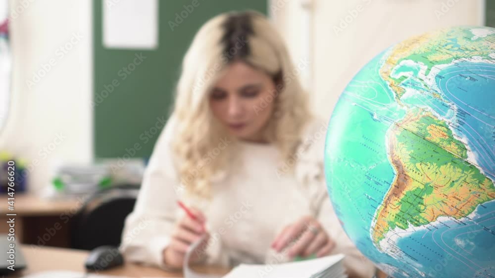Globe and school teacher, geography lesson concept. College lesson, teacher at the table Globe and school teacher, geography lesson concept. College lesson, teacher at the table