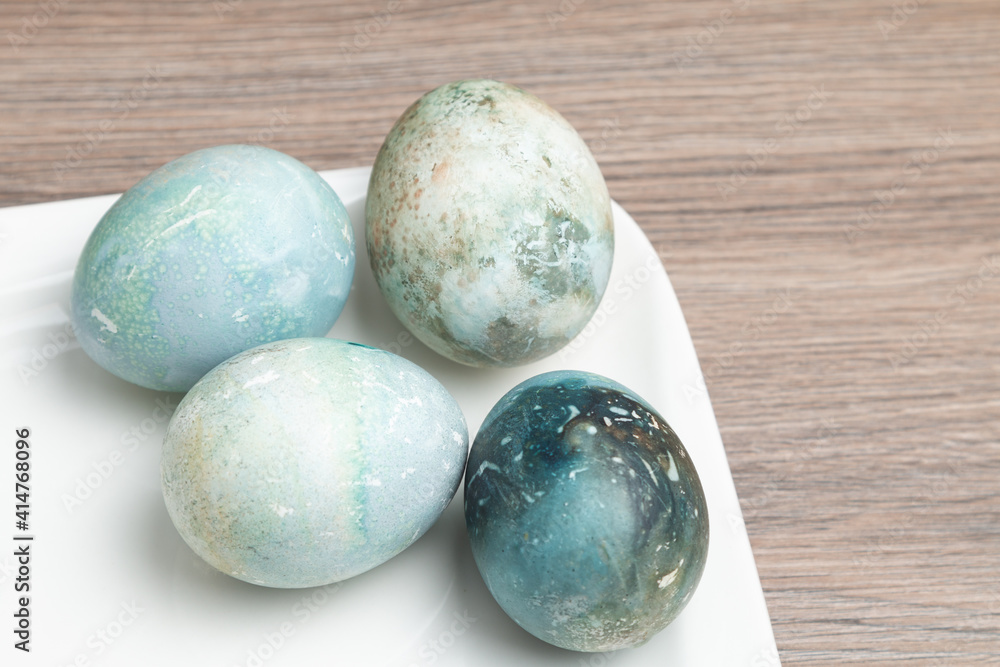 Easter painted eggs in a white plate on a wooden table Easter painted eggs in a white plate on a wooden table