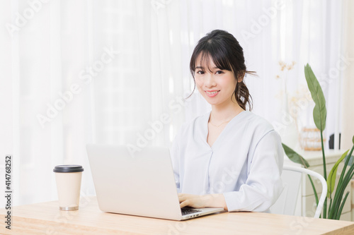 部屋でノートパソコンを使う若い女性