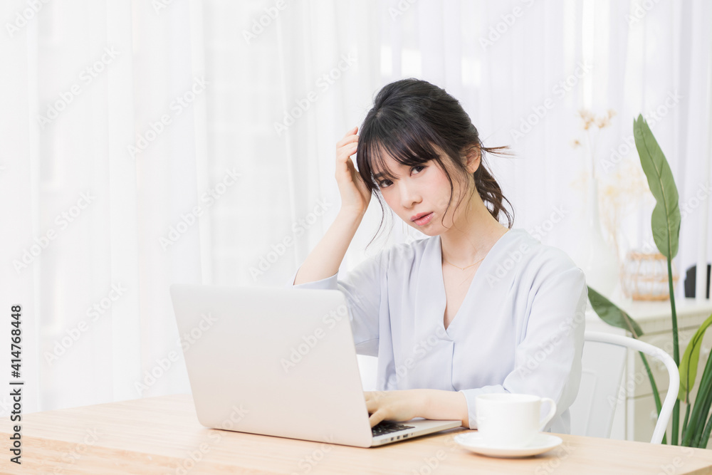 部屋でノートパソコンを使いながら悩む女性 部屋でノートパソコンを使いながら悩む女性
