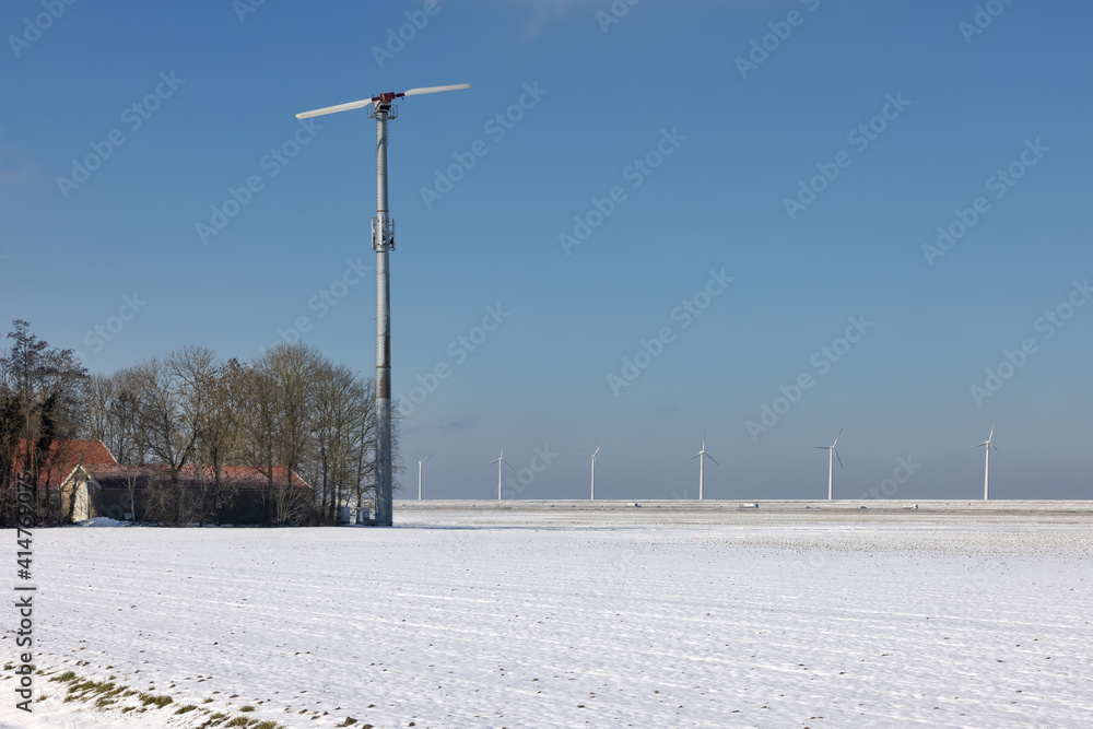 Dutch farmland covered by snow with farmhouse and wind turbine