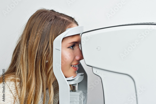 The doctor checks the patient's throat. Consultant in the ophthalmology office. Apparatus for checking vision on a white wall background.