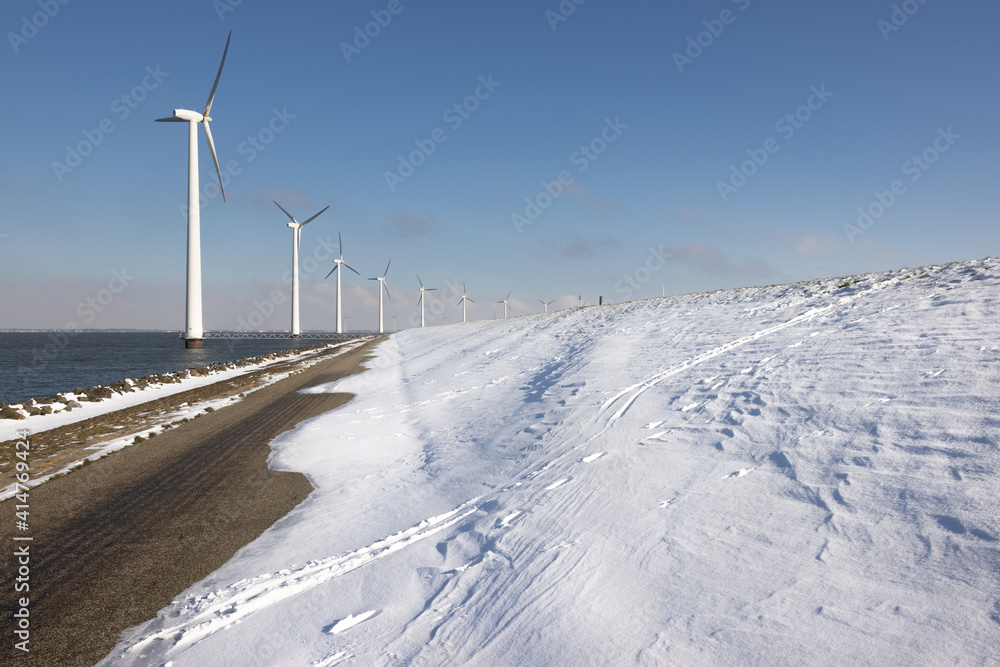 Row offshore windturbines along Ductch coast in winter with snow Row offshore windturbines along Ductch coast in winter with snow