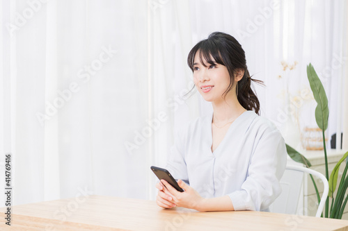 部屋でスマホを使う若い女性