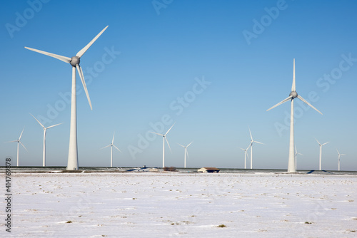 Dutch agricultural landscape with windturbines and fields covered with snow
