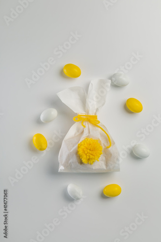 Easter concept - bunny shaped bag with eggs and flowers on bright yellow background, top view