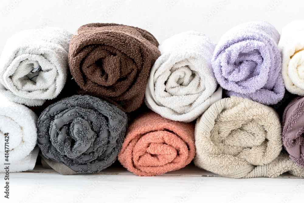 Fragrant and fresh multi-colored terry towels in a roll on a wooden white background. 100% cotton Fragrant and fresh multi-colored terry towels in a roll on a wooden white background. 100% cotton