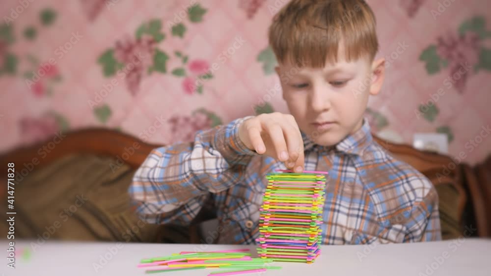 Boy builds a pyramid of colored sticks. Table games. Boy builds a pyramid of colored sticks. Table games.