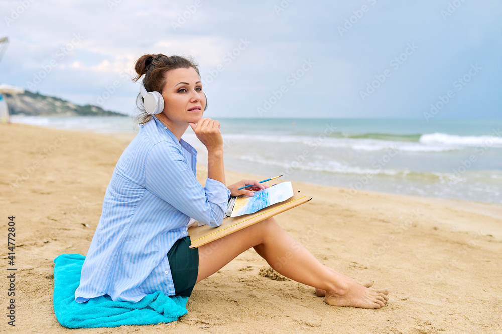 Mature woman with headphones listening to music enjoying watercolor painting