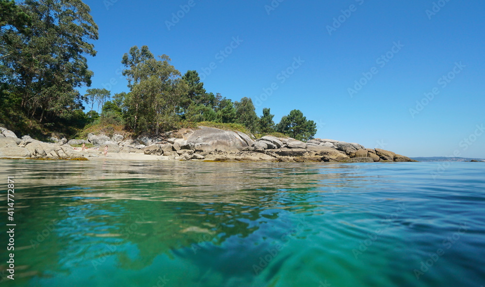 Spain Galicia rocky coastline with small beach in summer, seen from water surface, Atlantic ocean, Bueu, Pontevedra province