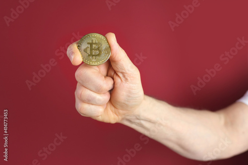 male hand hold coin gold bitcoin on red background, sale charts, up and down concept, banking, saving money, payments, e-business