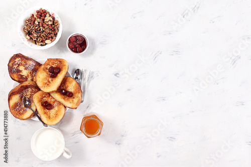 French toast and muesli on a gray table with berries and jam. Delicious healthy French breakfast. Top view, place for text. Minimalistic concept of a modern bakery. Selective focus