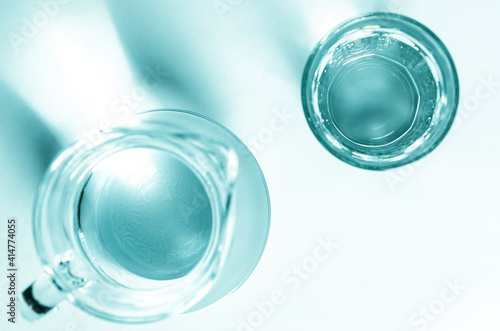 Pure clear water in a glass glass and glass jug stands on a white background