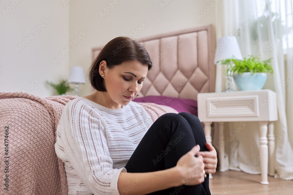 Unhappy tired depressed mature woman sitting at home on the floor Unhappy tired depressed mature woman sitting at home on the floor