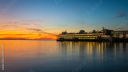 Ferry Boat on the sunset run prepares to sail towards the orange and gold colors of the setting sun