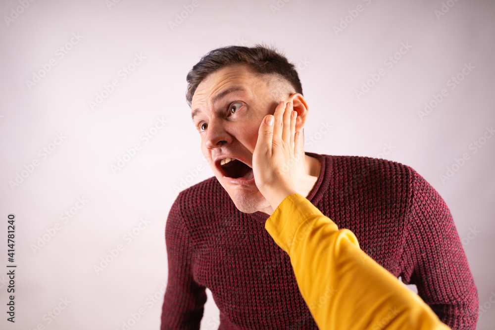 Crop person slapping scared man in face. Emotional male getting slapped in face while shouting with closed eyes in fear on white background Crop person slapping scared man in face. Emotional male getting slapped in face while shouting with closed eyes in fear on white background
