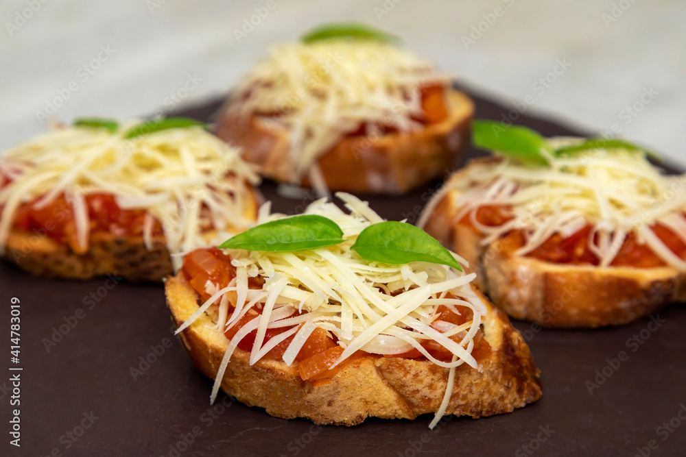 Bruschetta with tomato, basil and mozzarella cheese on wooden board. Traditional Italian appetizer or snack, antipasto
