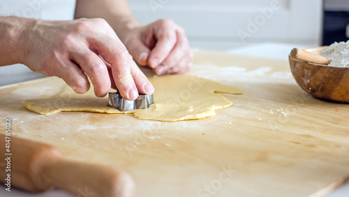 The process of making homemade asterisk shortbread cookies. Male hands cut cookies using a mold made of rolled dough. Authentic home hobby