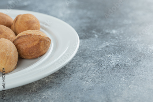 A white plate full of sweet walnut shaped cookies