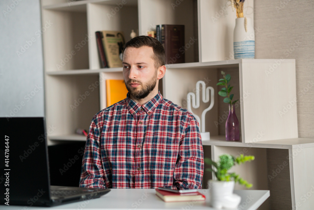 Fototapeta premium Focused young businessman wear headphones study online watching webinar podcast on laptop listening learning education course conference calling make notes sit at work desk, elearning concept