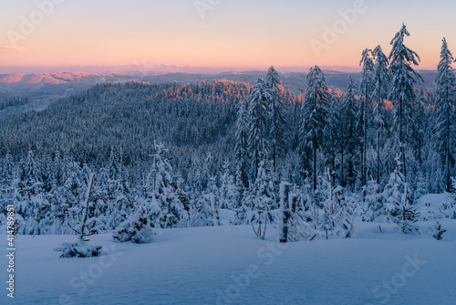 Sunset from the top of the mountain in Carpathian range. Landscape with winter forest and lots of snow. Glowing sky in the golden hour in Beskid mountains, Czech Republic.
