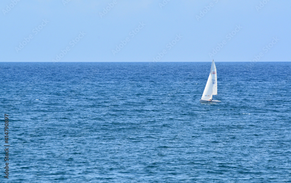 Fototapeta premium Una barca a vela naviga sul mare blu.