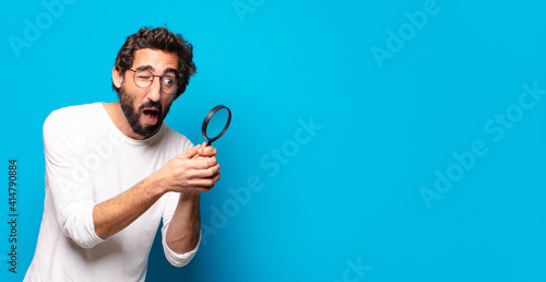 Konstfotografi young crazy bearded man looking and trying to find with a magnifying glass