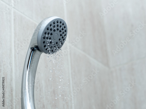 Shower head with low water stream. Broken shower in the bashroom photo