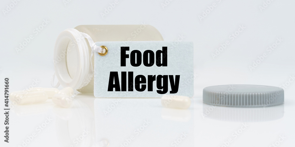 On a white reflective background, there are pills and a jar of drugs with a tag that says - Food Allergy