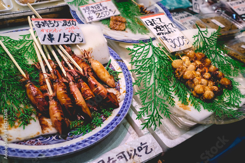 Cooked little squids and other seafood on skewers at Nishiki Market in Kyoto, Japan photo