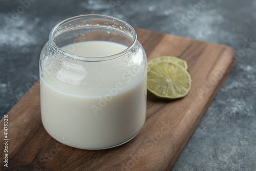 Glass of fresh milk and lemon slices on wooden board