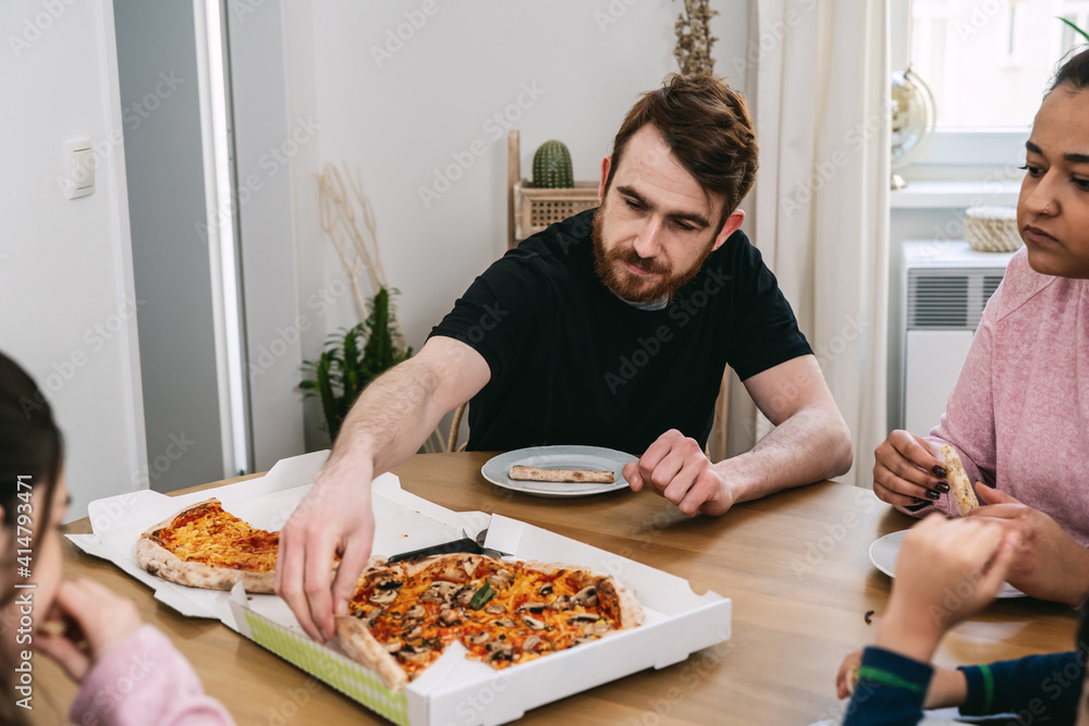 Mixed family eating vegan pizza with tomatoes, mushrooms and vegan cheese at home. Vegan food. Diversity and real people Mixed family eating vegan pizza with tomatoes, mushrooms and vegan cheese at home. Vegan food. Diversity and real people