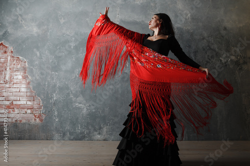 Young adult spanish woman dancing flamenco on gray vintage background